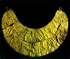 نمای کامل از سینه ریز زرین زیویه متعلق به دوران مادها با نقوش برجسته اساطیری و ردیف‌هایی از حیوانات در یک فضای تیره و مینیمال.