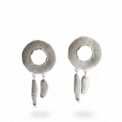 جفت گوشواره نقره‌ای دست‌ساز با بافت دایره‌ای شیاردار و آویزهای نامتقارن انتزاعی در پس‌زمینه سفید