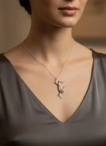 نمای نزدیک از گردن و چانه یک مدل با لباس ساتن تیره که گردنبند نقره فیگوراتیو سقوط اثر سونا یداللهی را به گردن دارد.